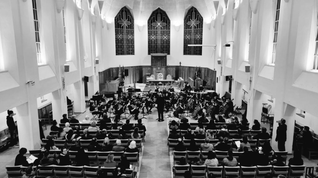 Black and white photo of an orchestra performing at the front of a church