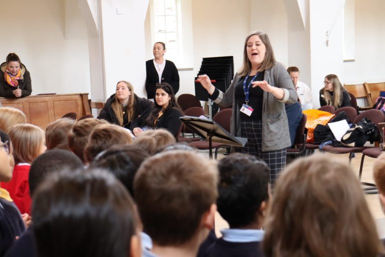 A choir leader leading a choir rehearsal with a group of students in a church