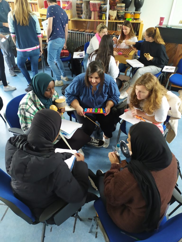 A group of adults sat in a circle playing tuned percussion