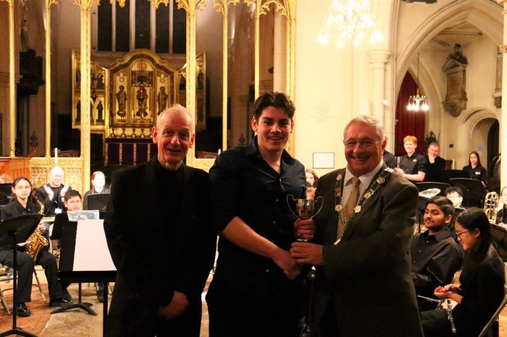 Student with conductor and deputy mayor receiving an award.