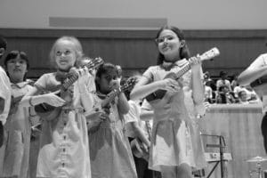 A black and white photo of two girls on stage playing the Ukulele