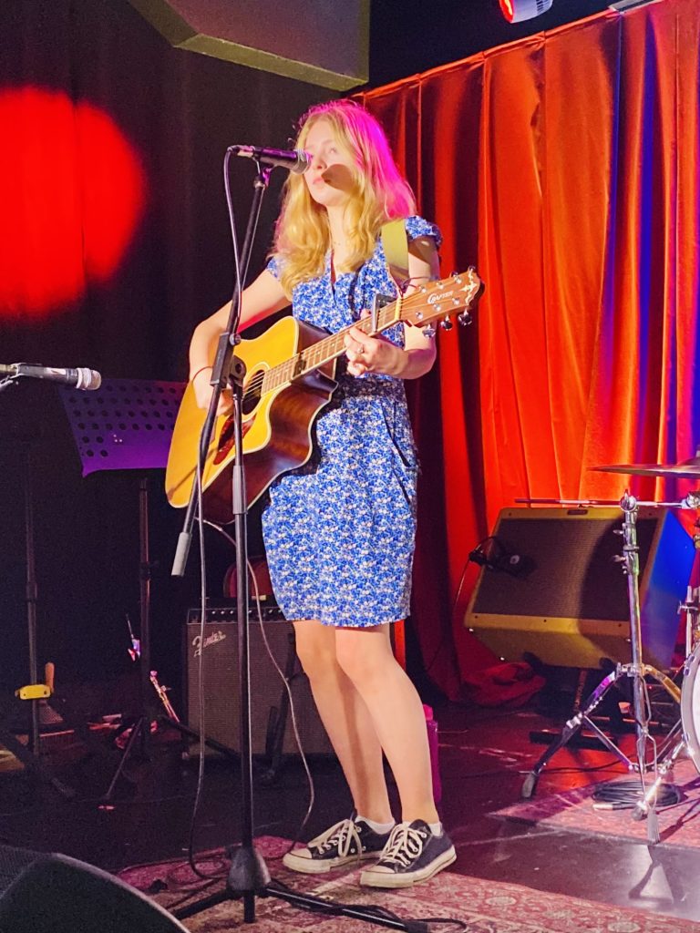 Image of a girl playing acoustic guitar on stage