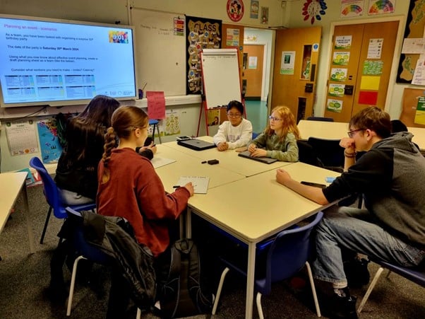 Students sat around a table in a classroom