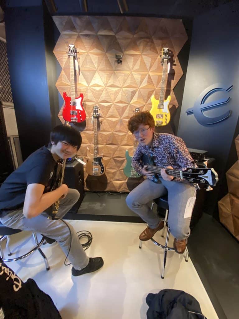 Two students playing guitars, looking at the camera
