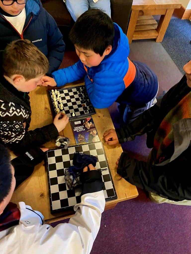 Students playing chess around a table