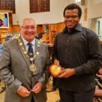 The Mayor of Sutton wearing chains and a student dressed in black. The student is holding an award plaque