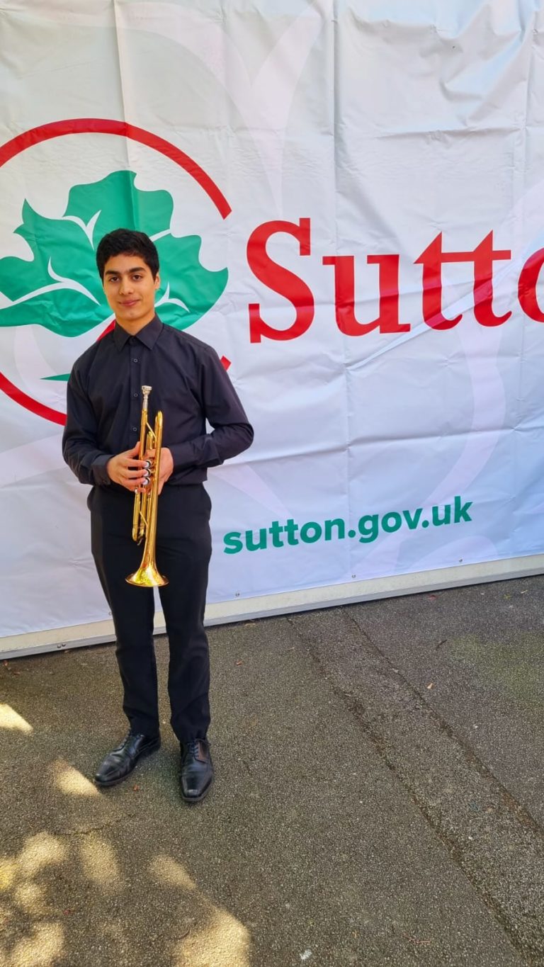 Young trumpeter standing in front of a banner with the Sutton Council logo