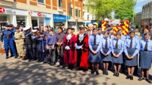Young trumpeter standing next to the Mayor and Deputy Mayor of Sutton. The trumpeter is dressed in black concert clothes, the Mayors in ceremonial outfits. They are surrounded by armed forces cadets