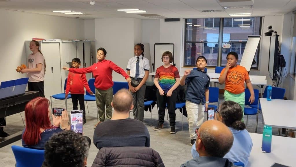A group of children performing in a large meeting room