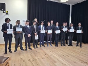 A group of students holding certificates in a school recital hall