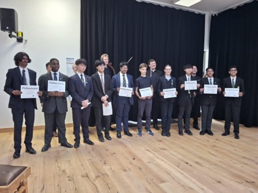 A group of students holding certificates in a school recital hall