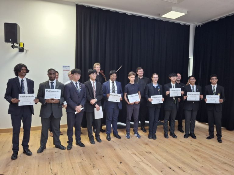 A group of students holding certificates in a school recital hall