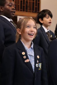 A young singer smiling into the camera, performing in a church