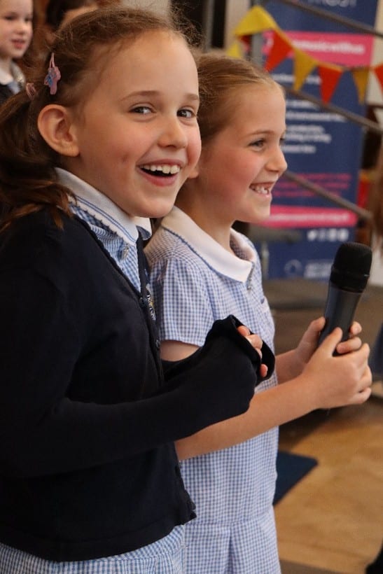 Two young singers smiling into the camera, performing in a church