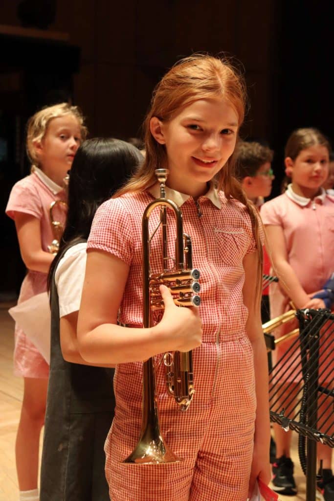 Image of a child smiling and holding a trumpet