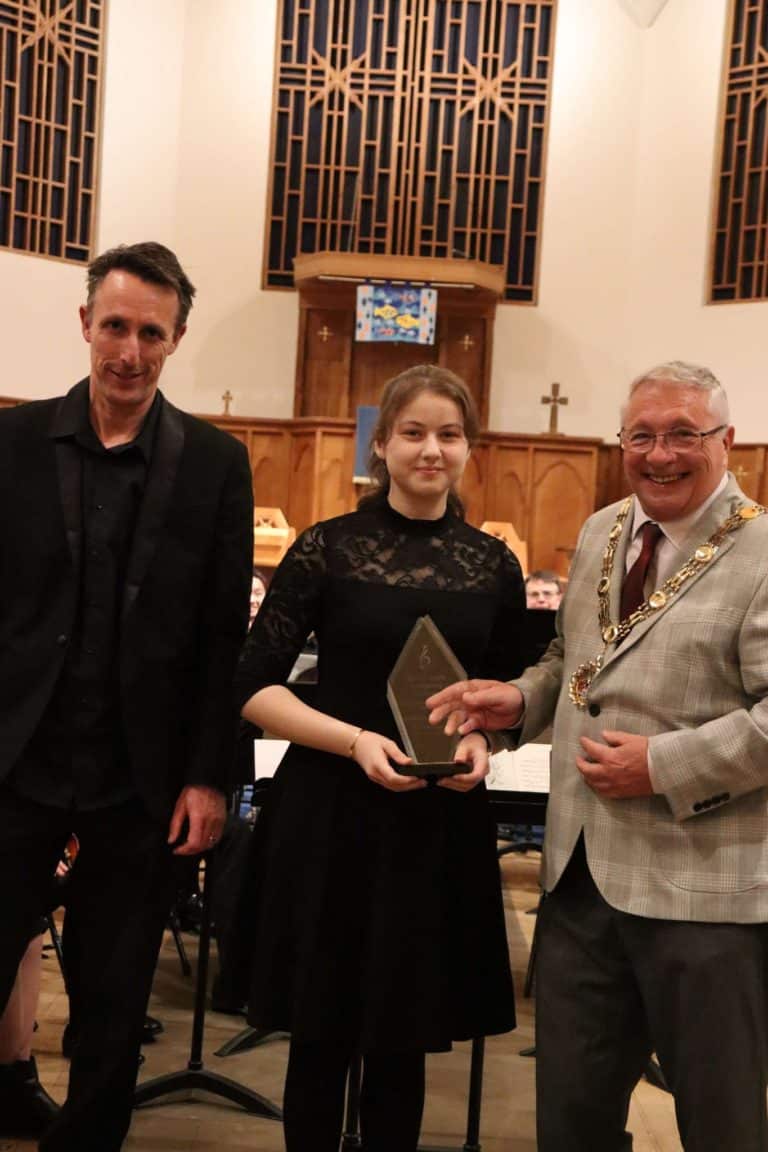 A student and conductor pose with a trophy