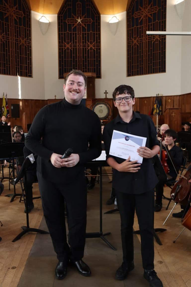 A student and conductor pose with a certificate