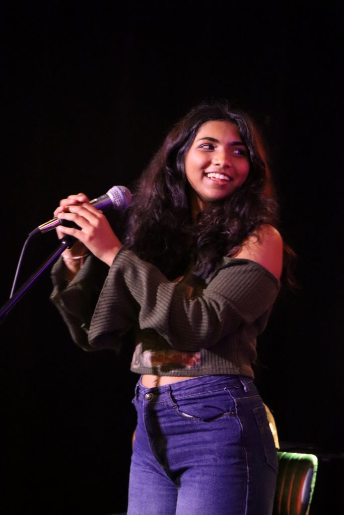 A smiling student on stage singing