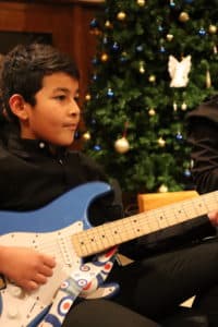 Guitarist playing in front of a Christmas tree