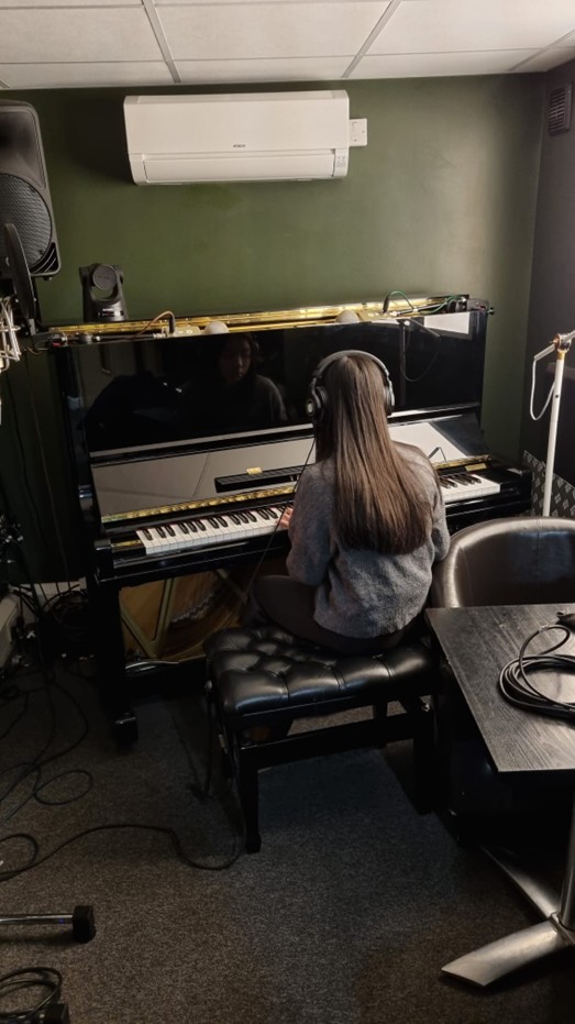 Student plays a piano in a recording studio