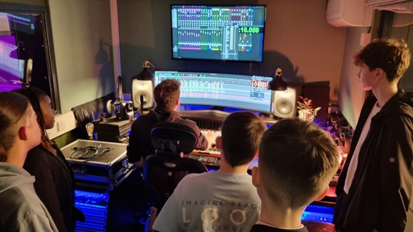 Students look at a computer in a recording studio
