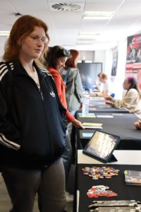 A student stands by a table with badges, flyers, and pencils on, learning more about music choices