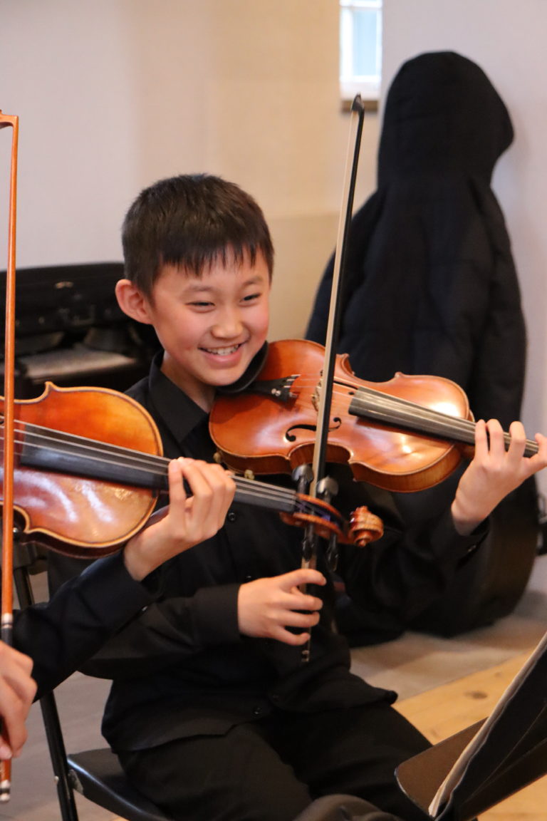 Student playing violin and laughing