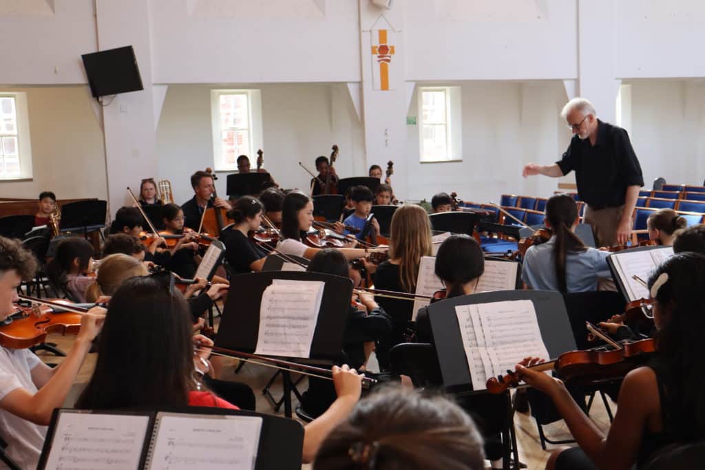 Student orchestra being led by a conductor