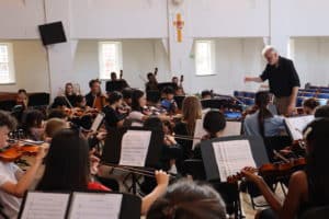 Student orchestra being led by a conductor