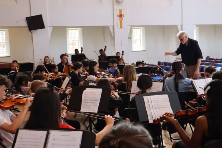 Student orchestra being led by a conductor