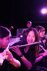 Female student holding a flute and smiling at the camera