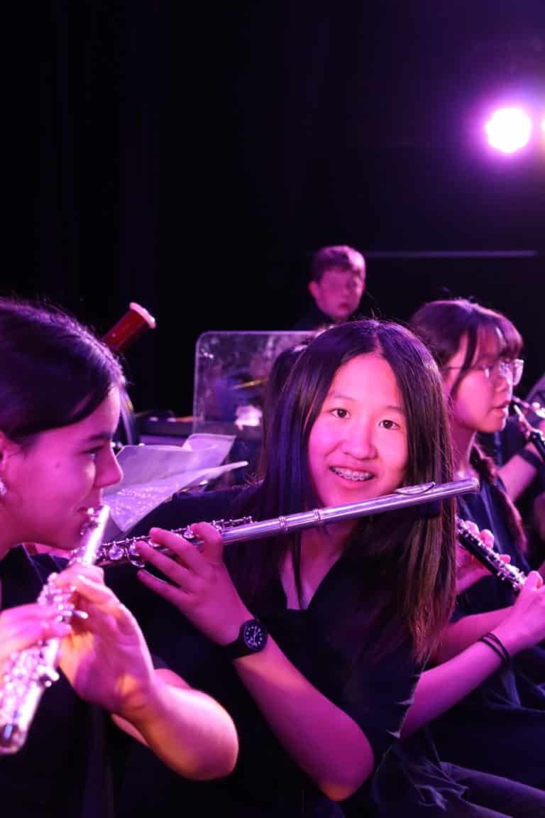 Female student holding a flute and smiling at the camera